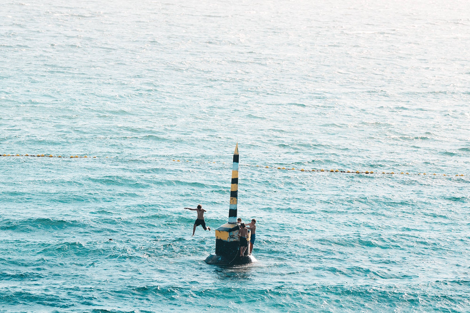 Kids leaping into the sea off a buoy